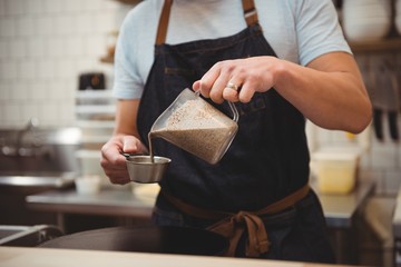 Chef pouring pancake mixture into measuring cup in kitchen