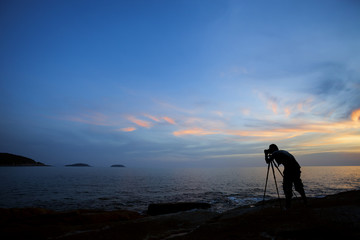 Silhouette of a photographer or traveler using a professional DSLR camera,photographer take sunset photo