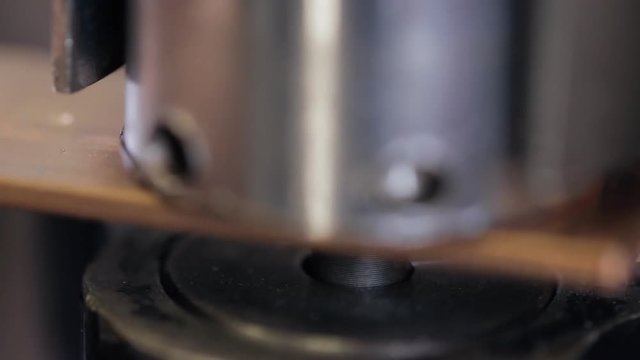 machine press makes hole in copper plate in house on construction site. Steel head with sharp tip pierces soft metal copper for base under switchboard. Holes inserted for mounting mechanisms wires