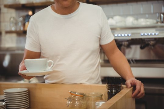 Male barista holding coffee at cafe