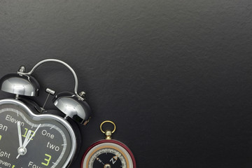 Alarm clock with compass on black background.