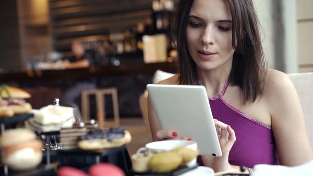 Happy, pretty woman using tablet and drinking coffee in cafe, 4K
