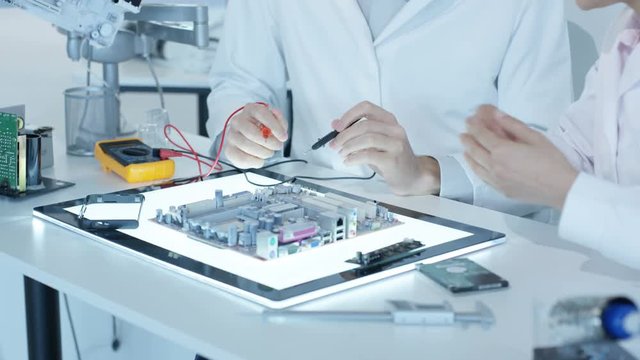  Electronics engineers working in lab building & testing electronic devices