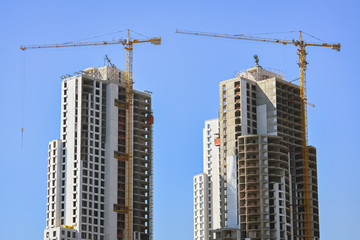 Fototapeta na wymiar Two skyscrapers and cranes