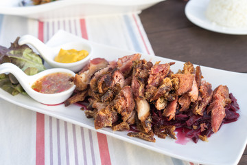 Slice of Fried pork leg with purple cabbage and spicy sauce.