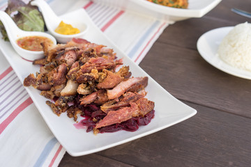 Slice of Fried pork leg with purple cabbage and spicy sauce.