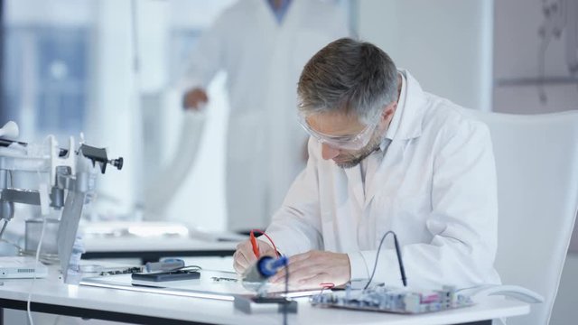  Electronics engineers working in lab building & testing electronic devices
