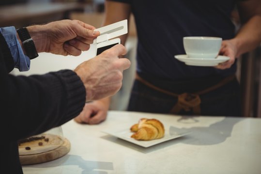Customer making payment with smartphone in coffee shop