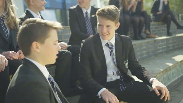  Happy school children chatting together outdoors in school yard