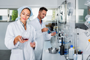 Two researchers in white coat checking wine acidity in laboratory