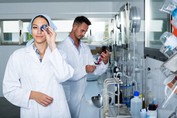 Fototapeta premium Woman expert in white coat testing wine in chemistry lab