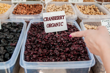 women selected organic dried cranberries. woman choosing dried berries sold by weight in organic boutique