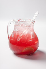 lemonade with strawberry, lemon and ice in a glass jug