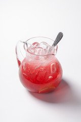 lemonade with strawberry, lemon and ice in a glass jug