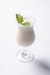 Delicious milkshake with a leaf of mint on top on a white background