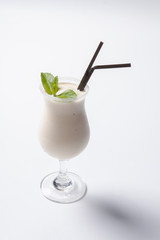 Delicious milkshake with a leaf of mint on top on a white background