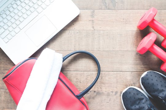 Flat lay of laptop computer and sport equipments on wood background. Workout and Healthy lifestyle, top view