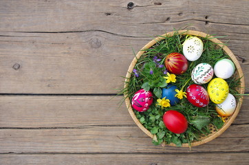 Easter eggs in the basket on rustic wooden background.