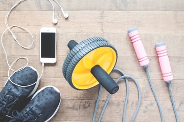 Flat lay of smartphone and sport equipments on wood background. Workout and Healthy lifestyle, top view
