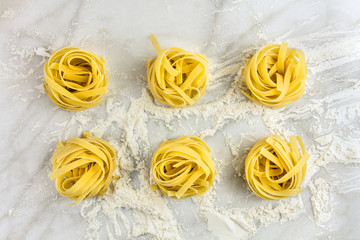 Overhead photo of pasta nests on white marble