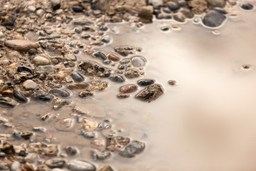Puddle on the road with stones as background