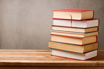 Stack of books on wooden table over rustic background with copy space