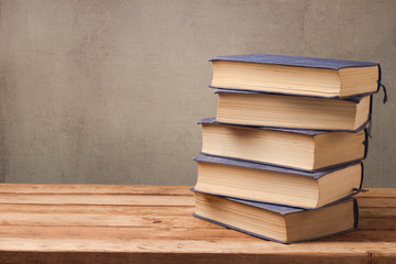 Old books stack on wooden table over rustic background with copy space