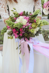 Elegance wedding bouquet of pink hydrangea and rose flowers with long silk ribbons in bride's hands.Close-up bunch of flowers. Bridal accessories in pink colors