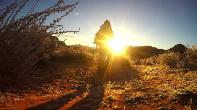 Pan of person walking on the sand past the sun.