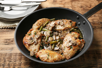 Frying pan with delicious chicken marsala on table