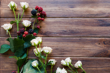 Elegant  floral background. Blackberries and rose bush on rustic wooden table