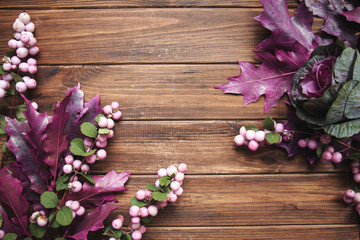 Snowberry and purple leaves on the wooden background with space for text