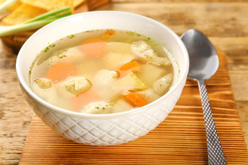 Plate with chicken soup on wooden board