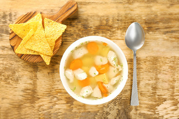 Plate with chicken soup on wooden table