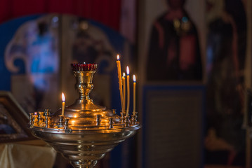 Burning church candles on a candlestick.  In the background is the interior of the church, the church.