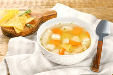 Plate with chicken soup on wooden table