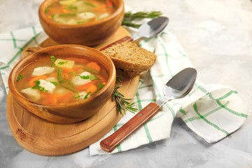 Crock pots with chicken soup on wooden board