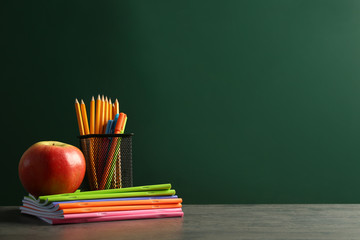 Stationery and apple on chalkboard background
