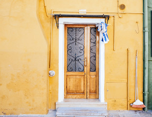 Beautiful house facade on Burano island, north Italy. Colorful yellow house wall with a door and windows