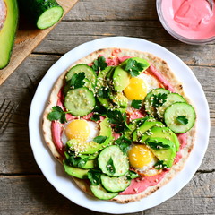 Tacos with fried quail eggs, avocado, cucumber, beetroot hummus and parsley. Delicious breakfast tacos on a plate and on vintage wooden table. Top view