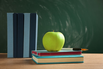Books and apple on chalkboard background