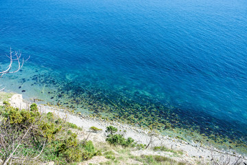 Blue sea, stones beach and cliff in the Mediterranean. Summer day on sea