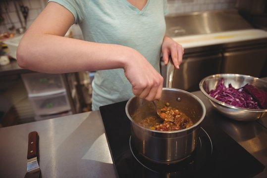Midsection of female chef cooking food in kitchen