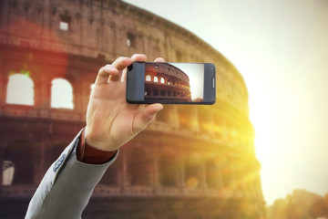 Tourist taking a picture in front of Colosseum at spring sunset, Rome, Italy. Travel concept