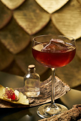 Fresh branded red alcoholic cocktail with a small bottle for alcohol and a red marmalade snack on a black stone bar counter.  Concept of alcoholic and non-alcoholic bar beverage.