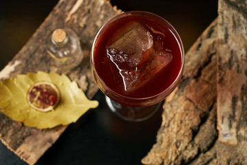 Fresh branded red alcoholic cocktail with a small bottle for alcohol and a red marmalade snack on a black stone bar counter.  Concept of alcoholic and non-alcoholic bar beverage.