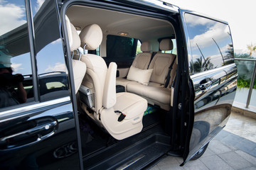 Car interior with beige leather  passenger seats. Open doors in a black car. Beige leather seats in an open black car