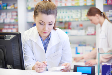 Female pharmacist working in drugstore .