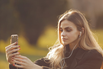 Beautiful young girl is doing selfie in the park