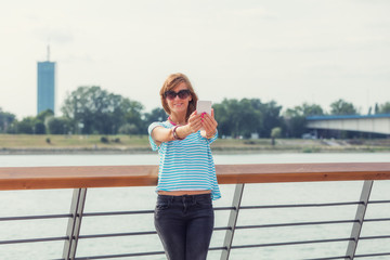 Girl using cellphone on the pier near the river.